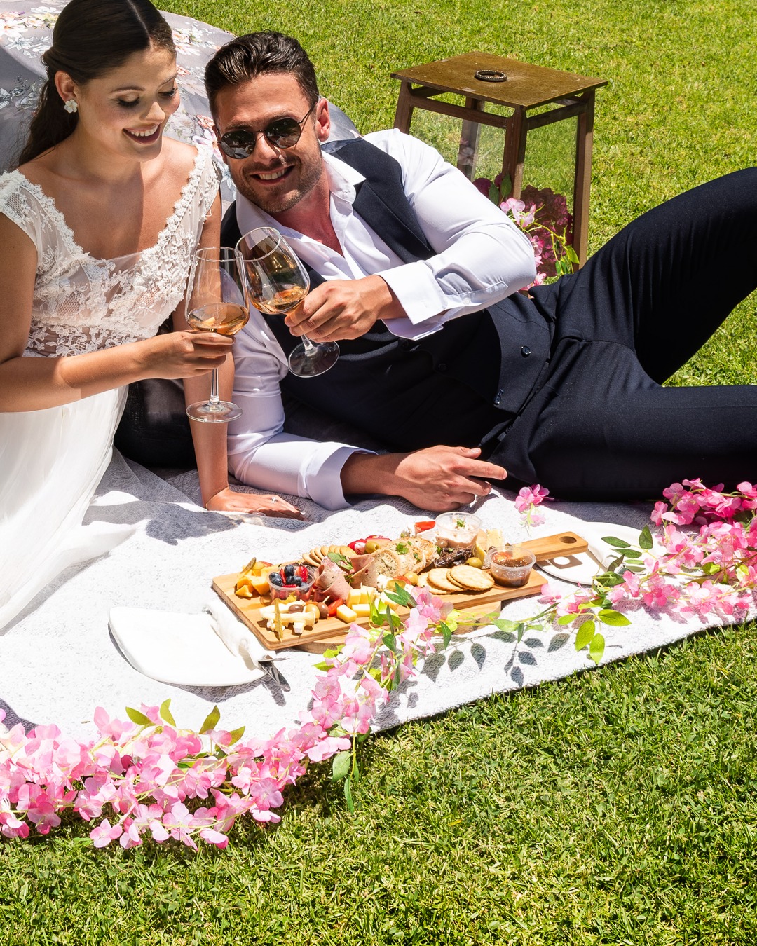 Newlywed couple toasting wine at a lawn picnic at Morgenhof Estate