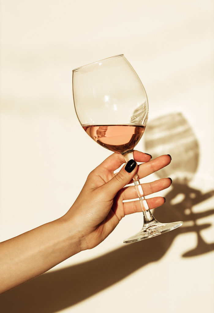 Hand holding a glass of rosé wine in the sunlight